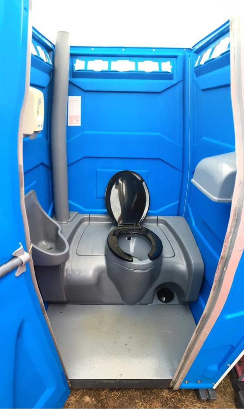 Construction worker beside a jobsite portable toilet